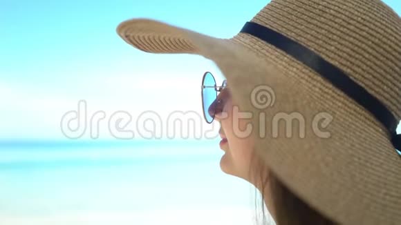 海滩上戴着帽子和太阳镜的美女画像视频的预览图