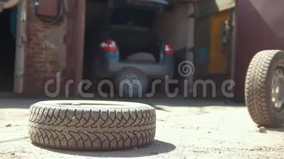 汽车轮胎在地面上向车库前的卧轮滚动视频的预览图