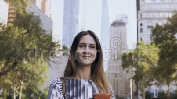 年轻快乐女商人站在美国纽约金融中心公园拿着文件的画像视频的预览图