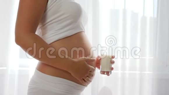 母亲美丽的孕妇从杯子里喝牛奶揉揉肚子视频的预览图