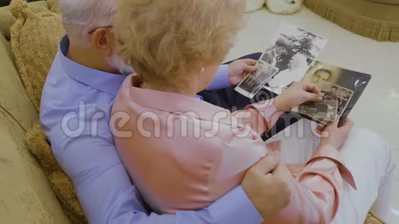 恋爱中的老夫妇看他们年轻时的照片视频的预览图