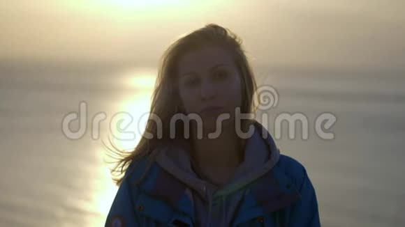 一张年轻女子微笑的特写照片红发随风飘扬望着夕阳身穿黄色衣服的女孩视频的预览图