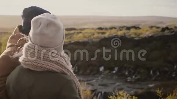 后景青年男女站在阳光明媚的山谷中欣赏冰岛美丽的景色视频的预览图