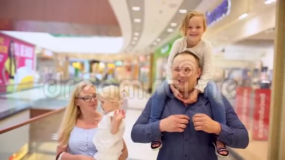 快乐的四口之家在购物在商场里的家人孩子们在购物中心和父母在一起家庭购物在大商店A视频的预览图