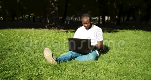 非裔美国人带着笔记本电脑在草地上视频的预览图