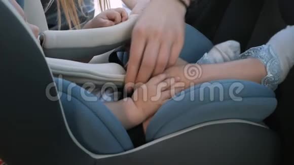 年轻母亲把孩子放在安全的汽车座位上视频的预览图