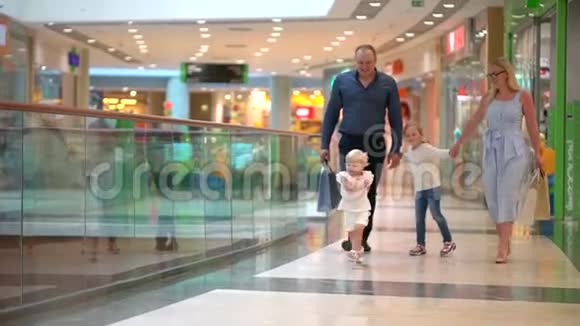 快乐的四口之家在购物在商场里的家人孩子们在购物中心和父母在一起家庭购物在大商店家庭视频的预览图