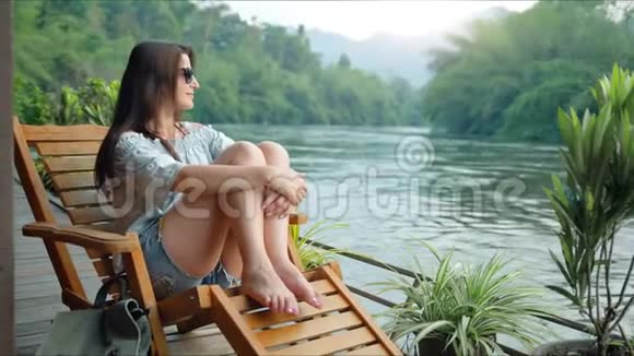 美丽的年轻女子旅行者在河边的山上休息视频的预览图