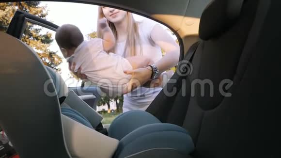 年轻母亲把孩子放在安全的汽车座位上视频的预览图