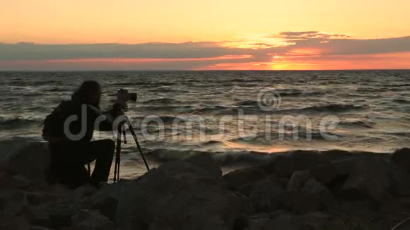 日落时拍摄海景照片的摄影师视频的预览图