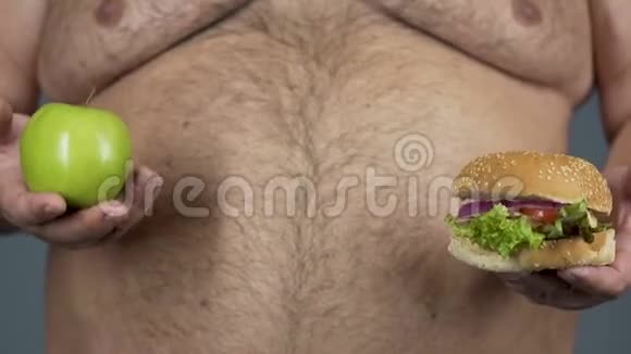 超重大肚子的男性选择汉堡代替苹果垃圾食品视频的预览图