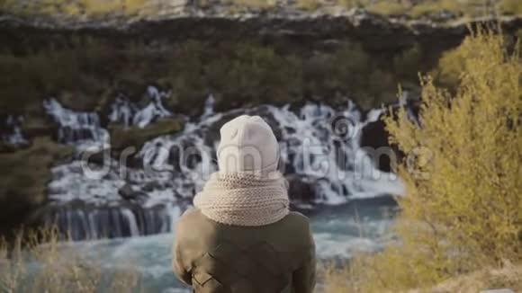 站在山谷中仰望冰岛瀑布探索自然的年轻女子背影视频的预览图