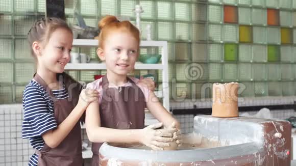 两个小女孩在陶轮上玩粘土玩得很开心视频的预览图
