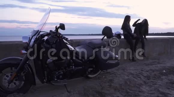 两个年轻的骑自行车的女孩在骑摩托车后在晚上的河堤上放松视频的预览图
