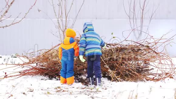 快乐村的孩子们穿着明亮温暖的衣服在花园里的灰色篱笆上从树枝上围着篝火玩孩子们哈视频的预览图