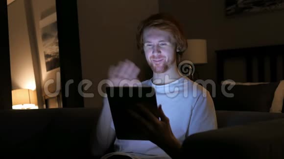 红发男子在平板电脑上夜间在线视频聊天视频的预览图