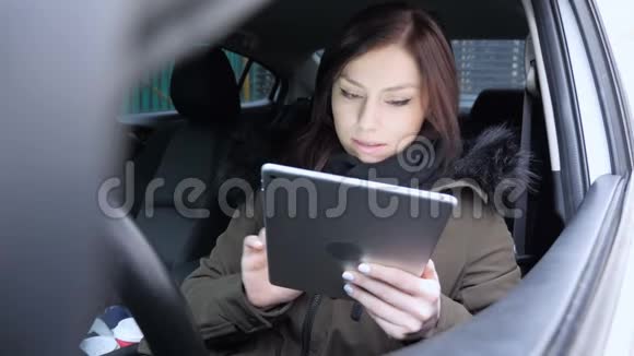 妇女在汽车中使用平板电脑时因损失而心烦意乱视频的预览图