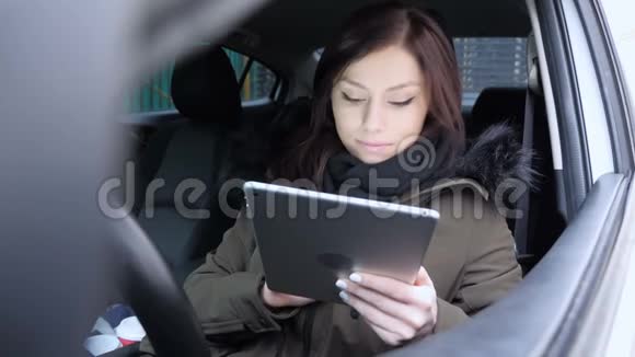 女人用平板电脑庆祝成功坐在车里视频的预览图