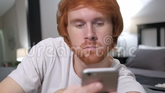使用智能手机浏览的休闲红发男子视频的预览图