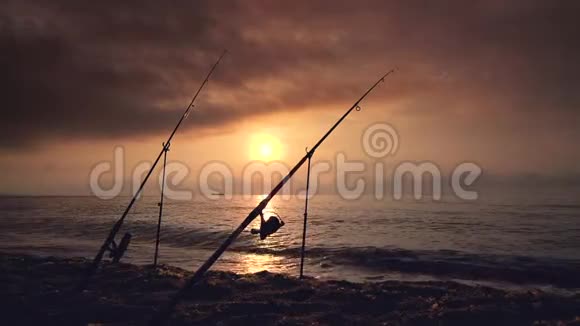 海面上美丽的日出日出海滩上的钓鱼竿和帆船视频的预览图