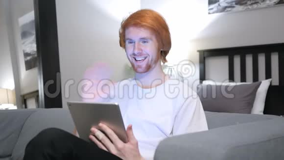 红发男子在卧室沙发上在线视频聊天视频的预览图
