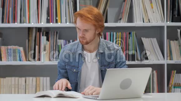 红发男子读书坐在图书馆视频的预览图