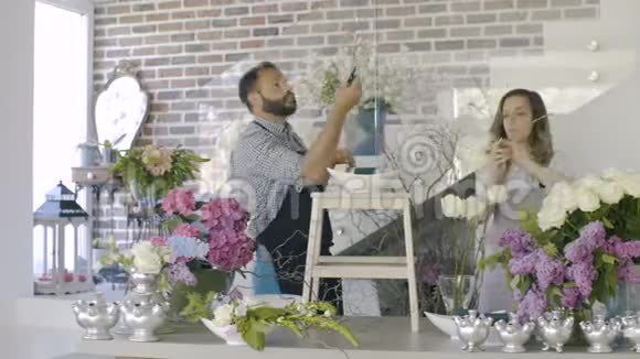 在花卉背景上花店里有一对漂亮的花匠工作视频的预览图