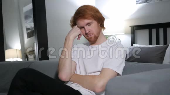 红发男子睡在卧室的沙发上视频的预览图