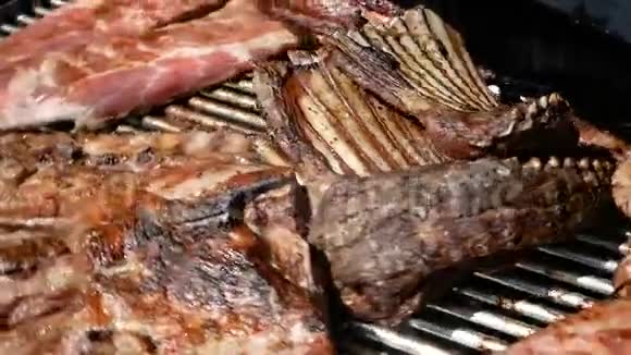 排骨牛排和烤肉串在一个大的旋转烤架上烹调在煤上准备肉的特写镜头视频的预览图