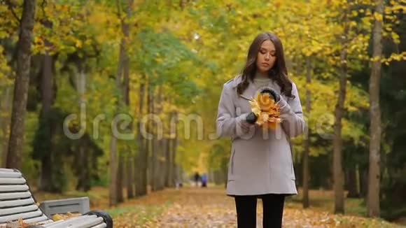 秋天伤心美丽的年轻女子在公园里走来走去坐在长凳上等着别人视频的预览图