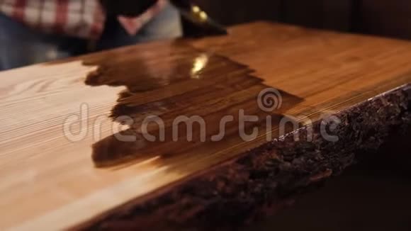 一个人用刷子把一根木梁画成一根木梁把的手收起来视频的预览图