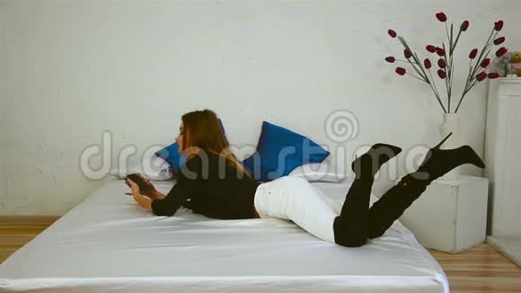 苗条的女孩躺在床上的靴子里拍了一张照片视频的预览图