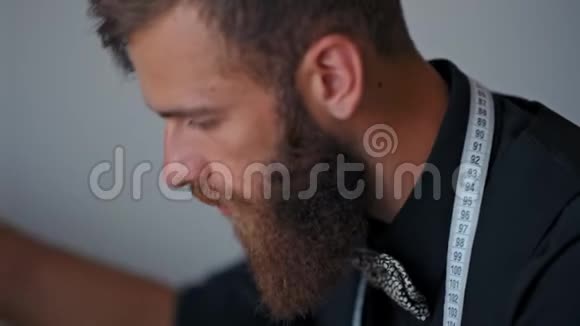 英俊的长胡子设计师正在自己的内衣里缝制时髦的衣服视频的预览图