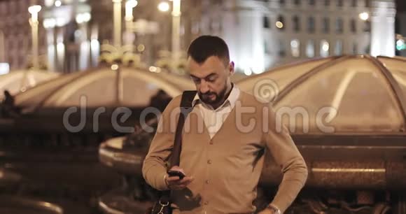 中年留胡子的男人在一个夜城的背景下接电话视频的预览图