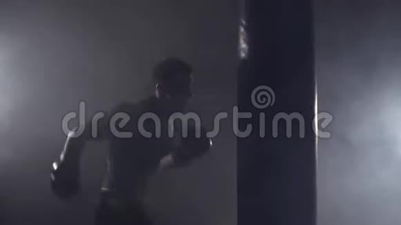 拳击手在黑暗的健身房打拳击袋在室内训练的年轻人视频的预览图