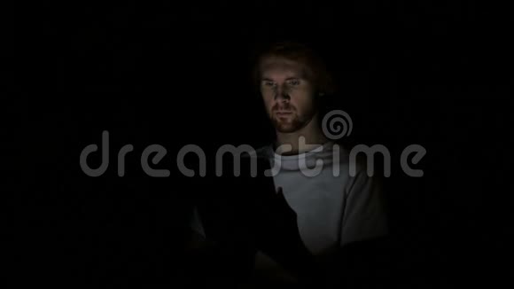 红头发的人忙着在晚上的平板上浏览视频的预览图