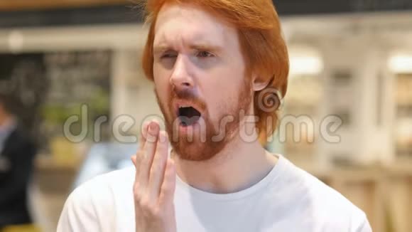 疲惫的红头发胡须男在咖啡馆打哈欠室内视频的预览图