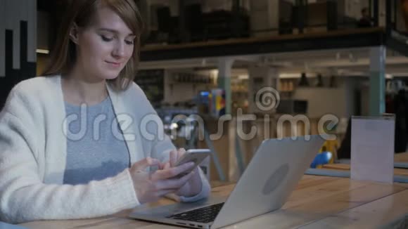 在咖啡馆里用智能手机打短信的年轻女性视频的预览图
