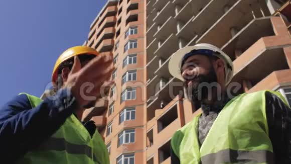 两名戴着胡须和胡子的头盔的施工管理人员在施工现场讨论施工细节4k视频的预览图