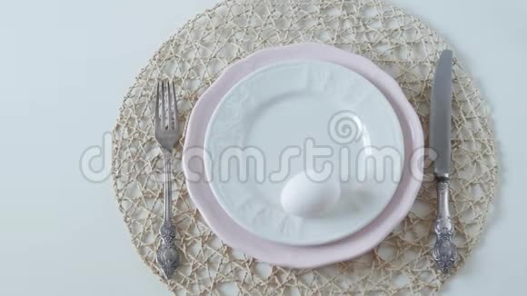 桌子设置白色背景上的白色菜肴早餐煮鸡蛋雌性手在盘子里下蛋视频的预览图