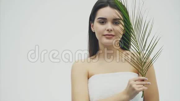 年轻美丽的微笑模特自然化妆长长的睫毛和绿叶的蕨类植物水疗护肤和健康视频的预览图