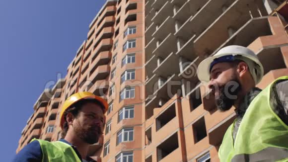 两名戴着胡须和胡子的头盔的施工管理人员在施工现场讨论施工细节4k视频的预览图