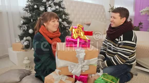 一个男人和女孩从一堆礼物中拿出礼物并打开它们圣诞节的主题视频的预览图