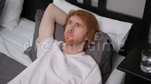 可怜的红发男子躺在床上休息思考视频的预览图