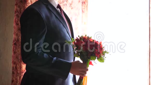 男人手中的美丽花朵是送给他心爱的女人的礼物穿着夹克的男人手里捧着一束美丽的红玫瑰视频的预览图