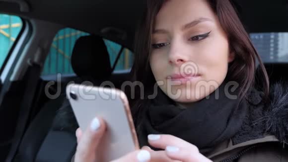 坐在车里的女孩在智能手机上浏览视频的预览图