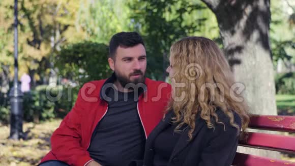 快乐的一对夫妇坐在公园的长凳上视频的预览图