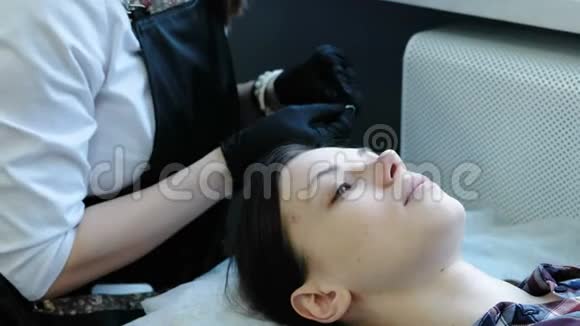 美容治疗美容师在女人的眼睛下面贴补丁侧视视频的预览图