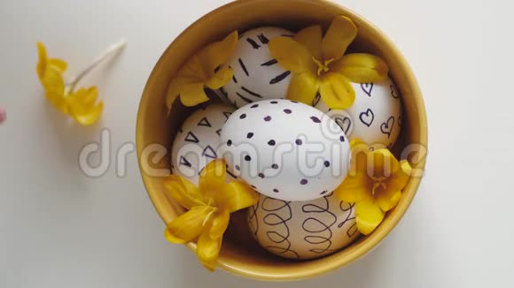 白色背景上的黄色杯子和复活节彩蛋雌性手拿着桌子上的鸡蛋移动杯子复活节彩蛋视频的预览图