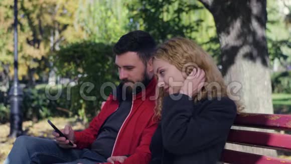 快乐的一对夫妇坐在公园的长凳上视频的预览图